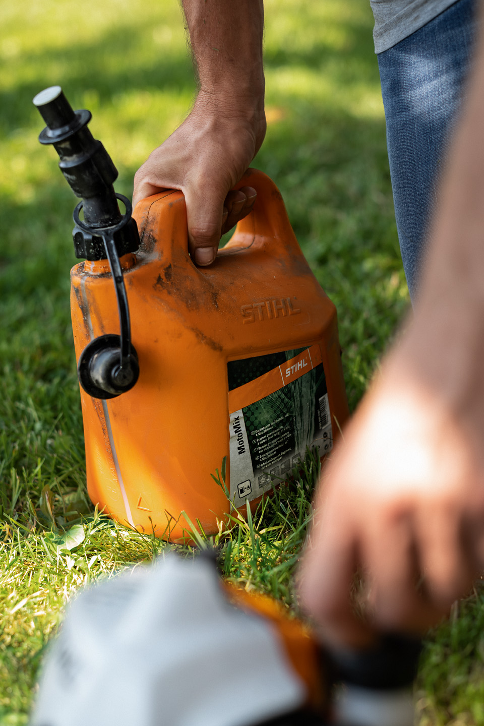 Egy férfi STIHL MotoMix üzemanyag-keveréket tartalmazó kannát tart a kezében