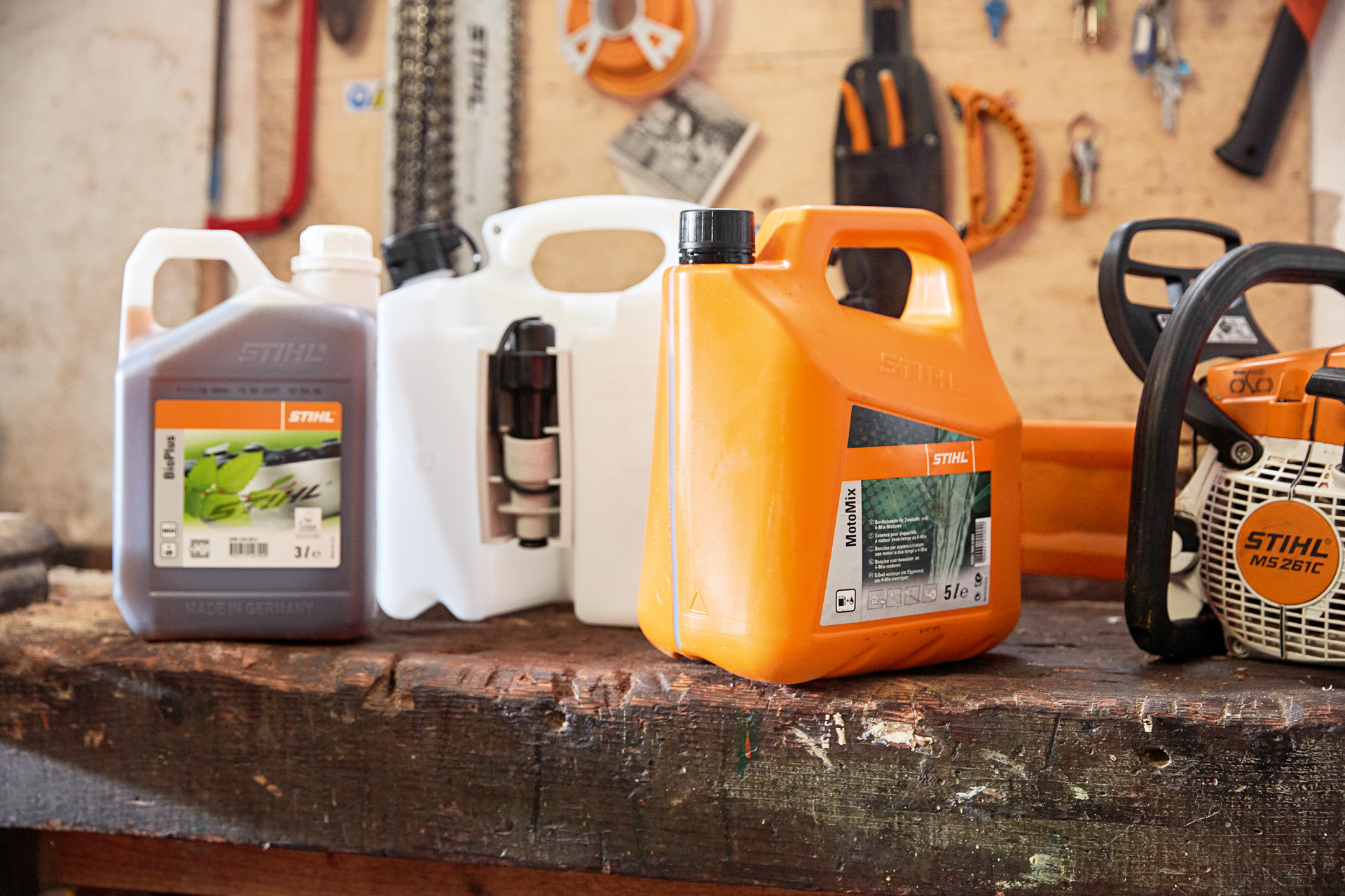 STIHL MotoMix üzemanyag-keveréket tartalmazó kanna, olaj és benzin, valamint MS 261 C STIHL benzines motorfűrész egy műhelyben