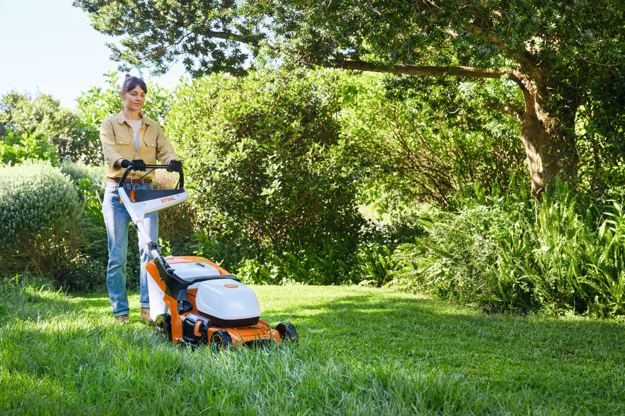 Egy hölgy egy STIHL RMA 448 PV típusú akkumulátoros fűnyíróval füvet nyír