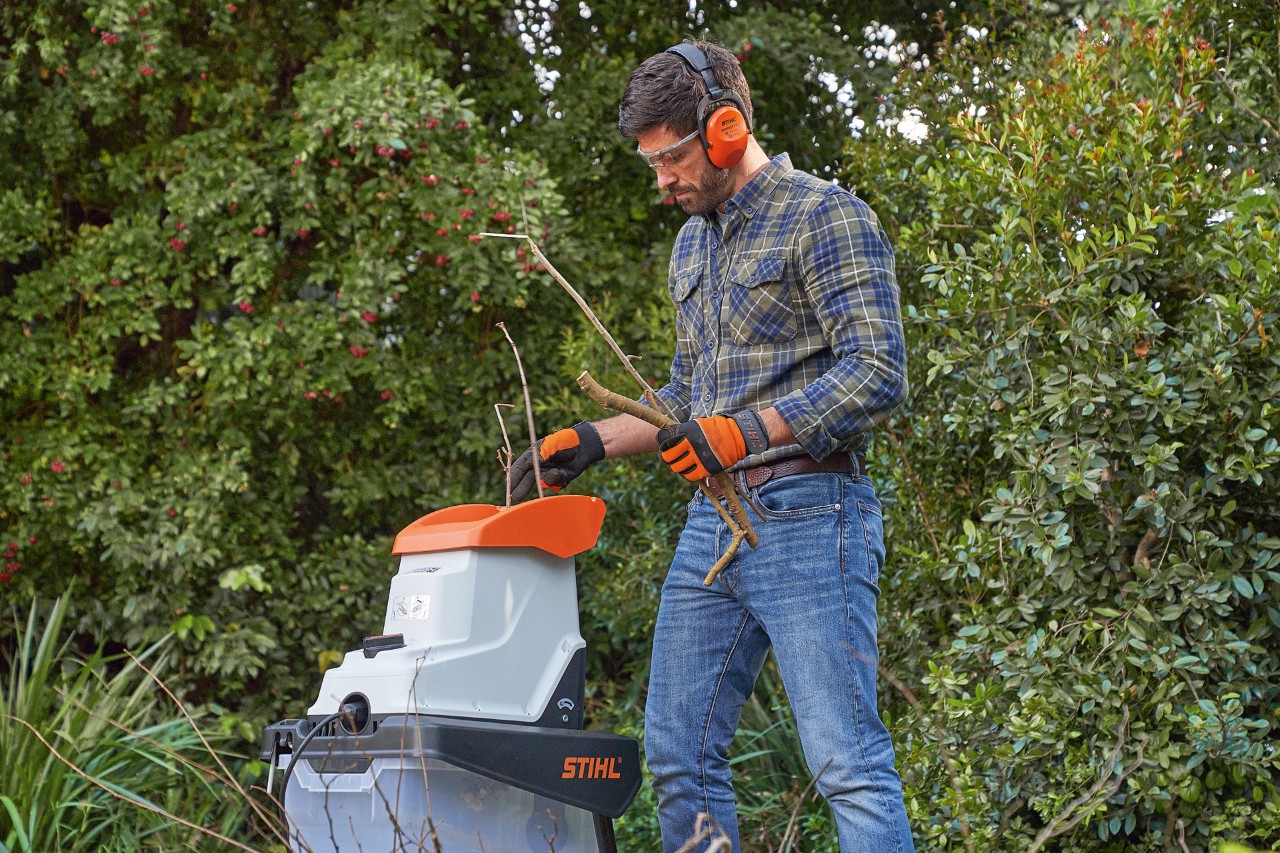 Egy védőfelszerelést viselő férfi STIHL aprítógépet használ gyallyak aprításához  