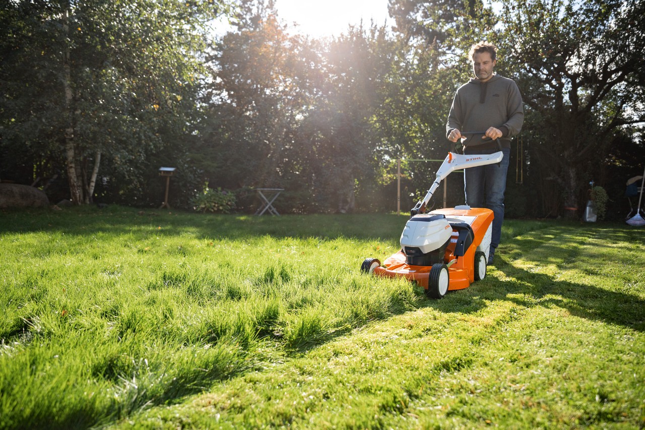 Egy férfi STIHL RMA 448 VC akkumulátoros fűnyíróval nyírja a gyepet a telkén