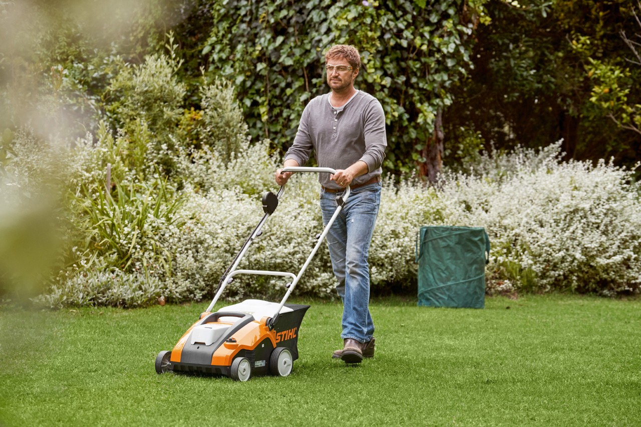 Egy férfi egy STIHL RLA 240 akkumulátoros gyepszellőztetővel lazítja a zöld gyepet