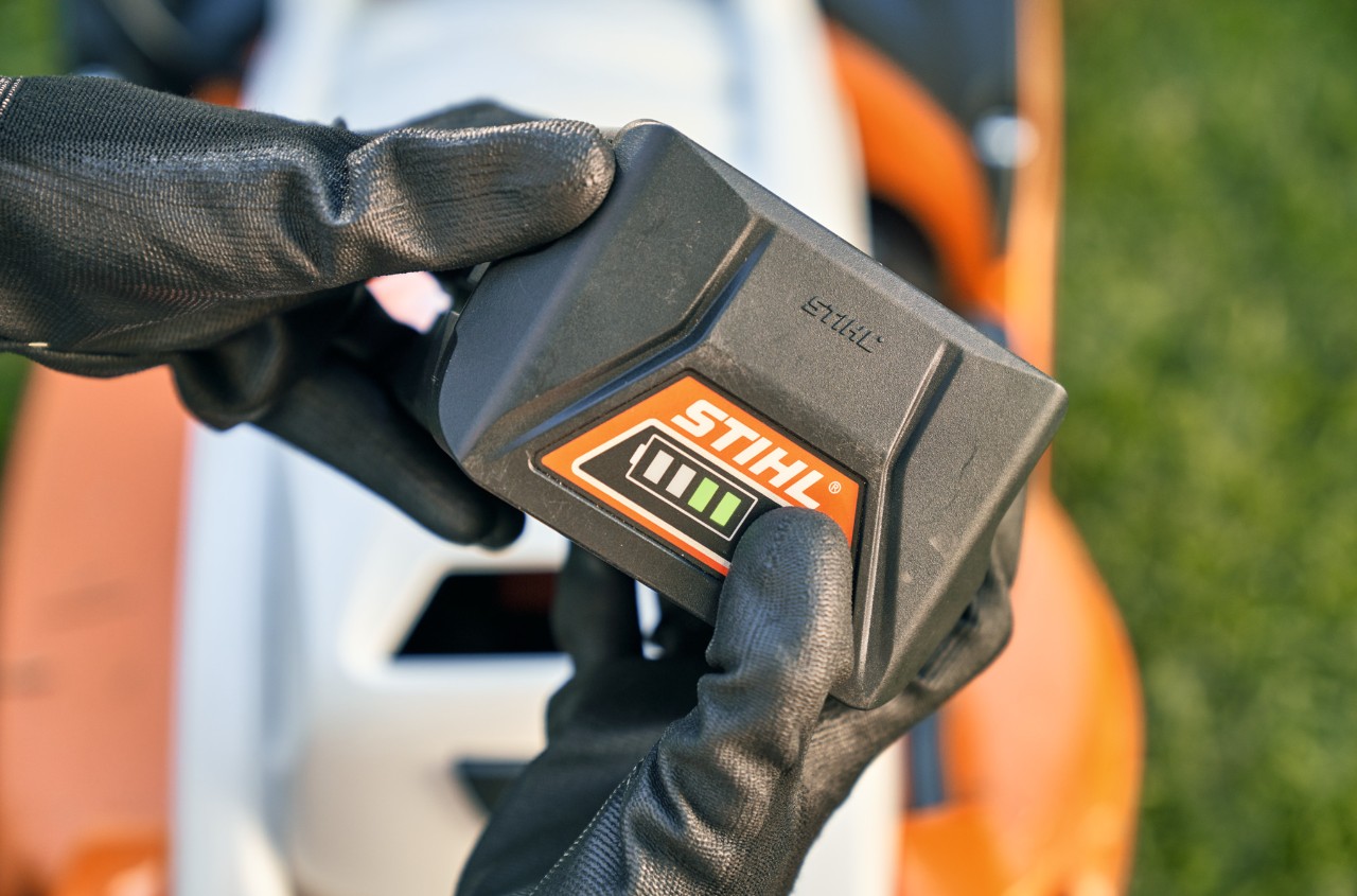 STIHL lítiumion-akkumulátor, a háttérben egy STIHL RMA 339 akkumulátoros fűnyíró