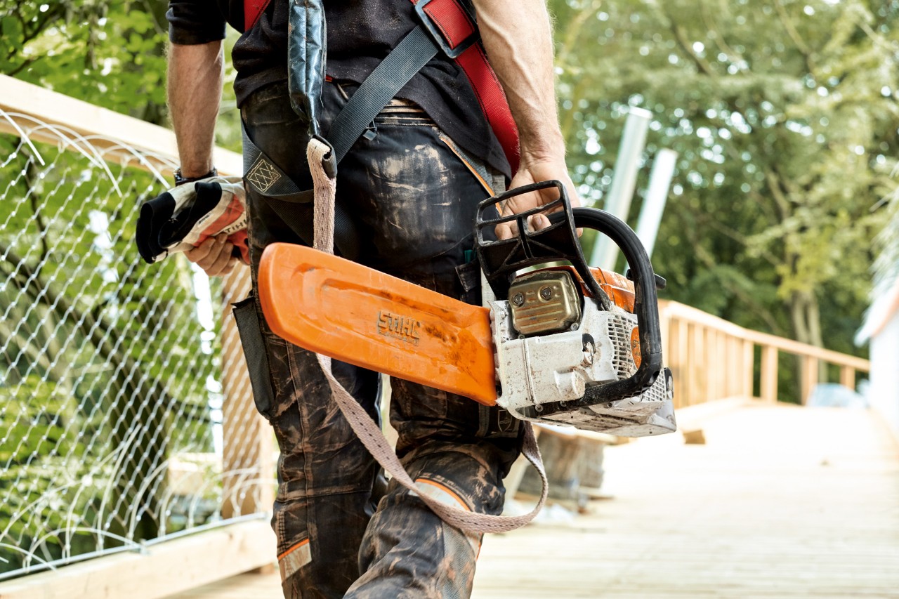 Védőruházatban dolgozó férfi egy láncvédővel ellátott STIHL MS 261 benzines motorfűrésszel.