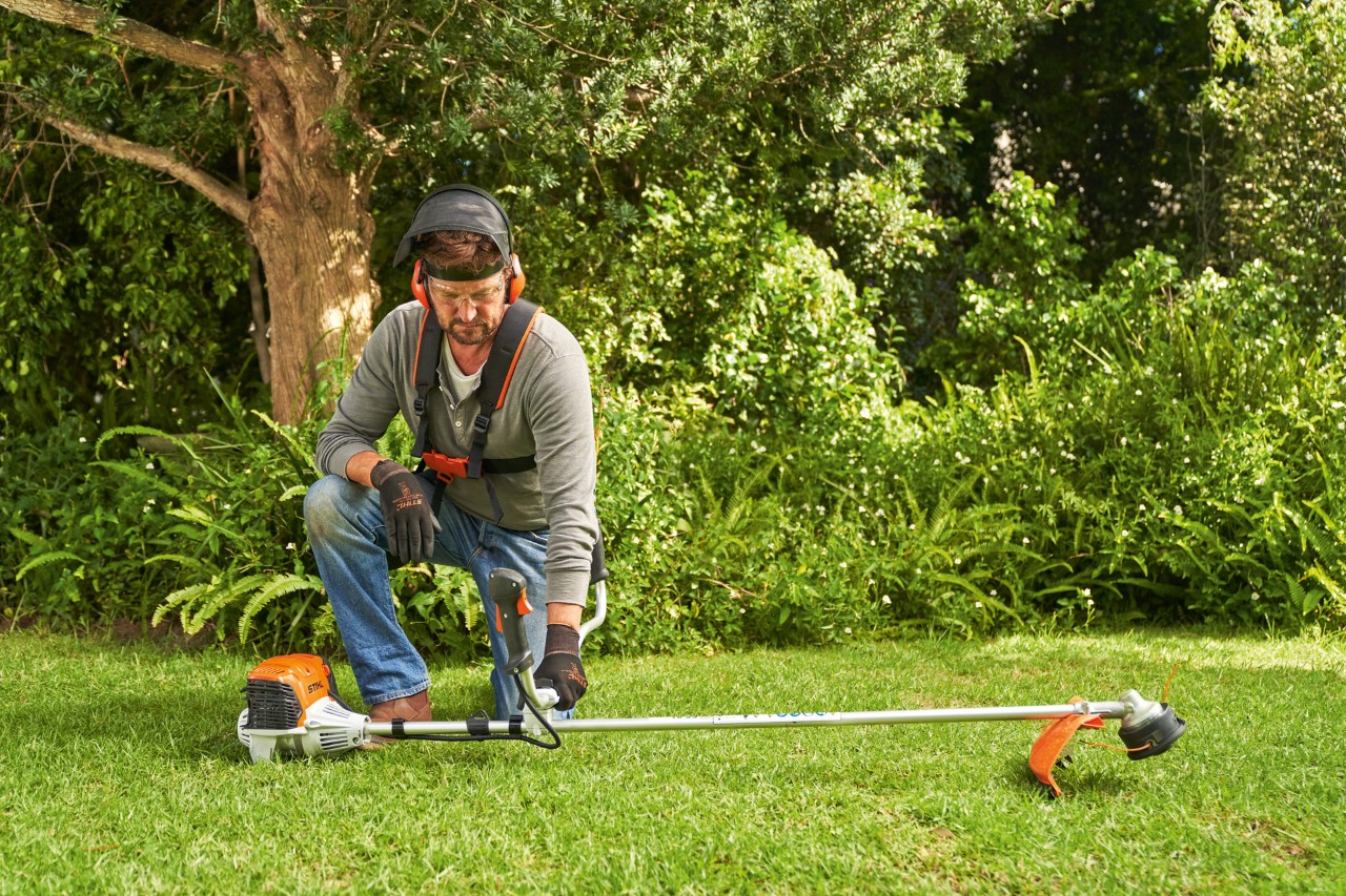 Egy férfi az indításhoz a földre helyezi a STIHL FS 91 benzinmotoros kaszát