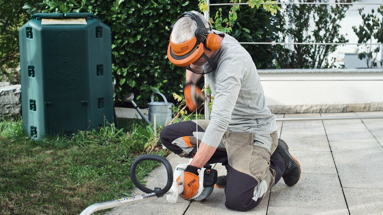 A védőruházatban dolgozó férfi meghúzza a STIHL FS 38 benzinmotoros kasza indítózsinórját