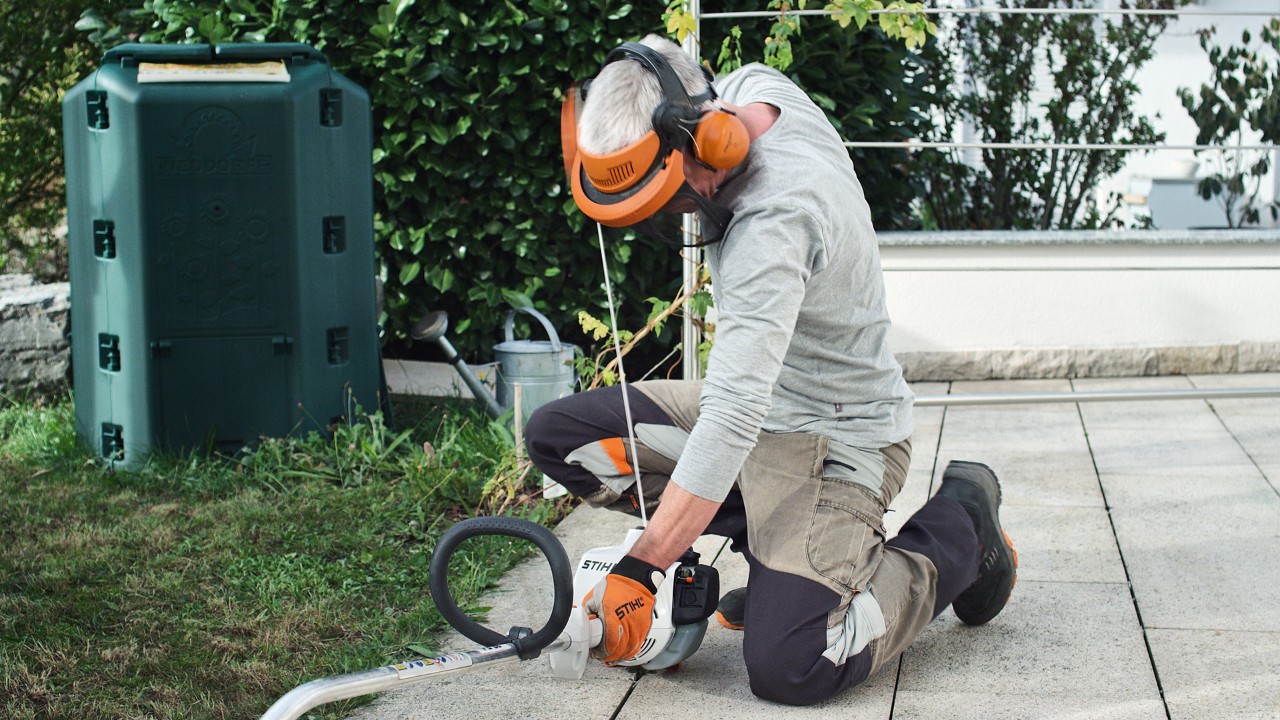 A védőruházatban dolgozó férfi újra meghúzza a STIHL FS 38 benzinmotoros kasza indítózsinórját