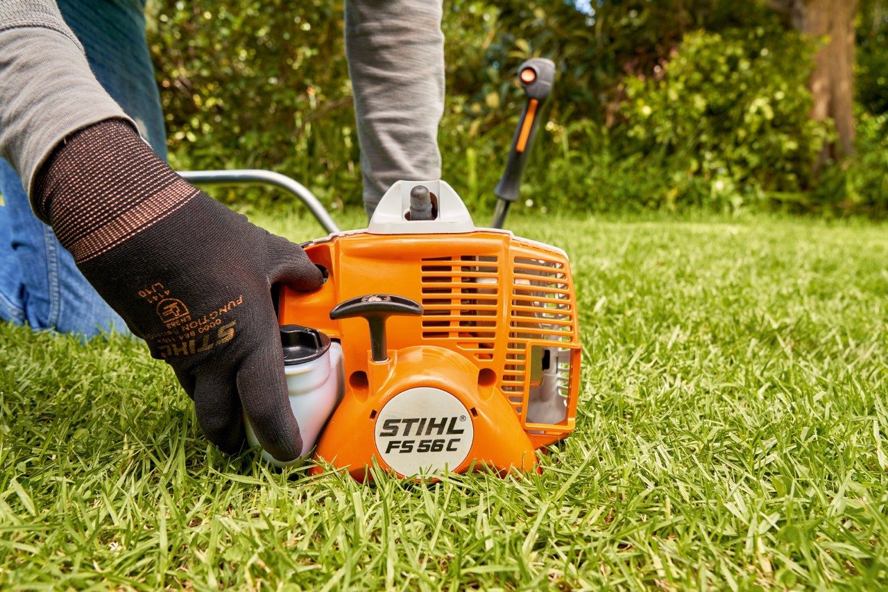 Egy férfi megnyomja a STIHL FS 56 benzinmotoros kasza üzemanyag-szivattyúját a beindításhoz
