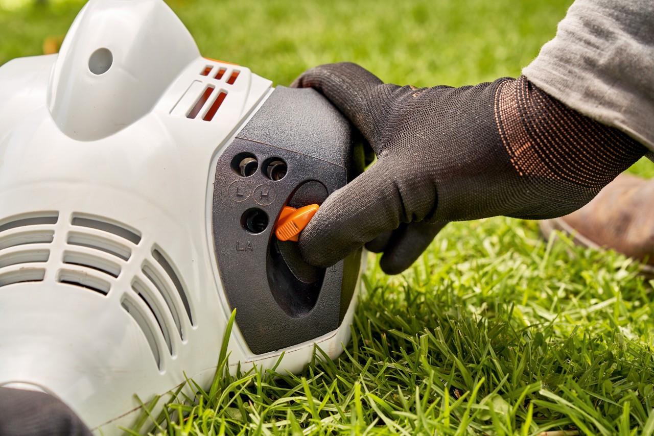 Egy férfi beállítja a STIHL FS 56 benzinmotoros kasza karját a beindításhoz