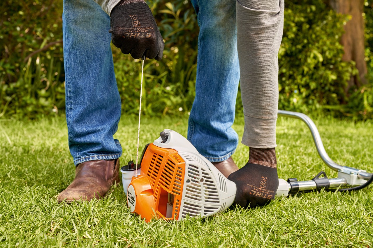 Egy férfi meghúzza a STIHL FS 56 benzinmotoros kasza indítózsinórját 