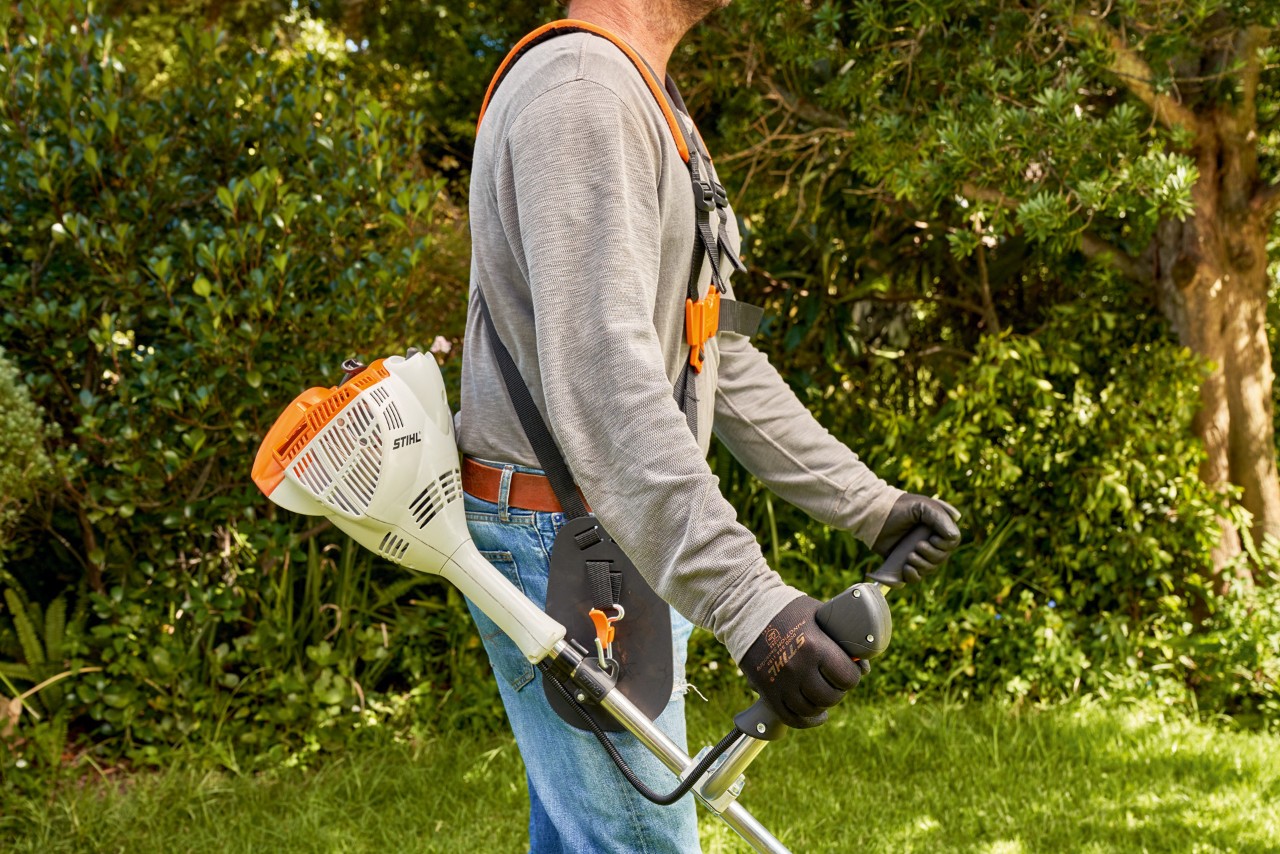 Egy férfi felemeli a STIHL FS 56 benzinmotoros kaszát a földről