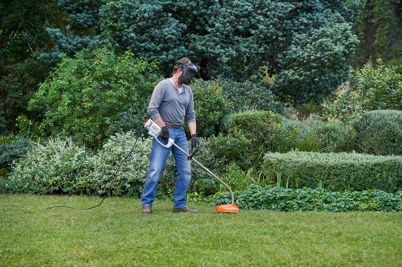 Egy STIHL FSE 60 elektromos szegélynyírót tartó férfi stabil testhelyzetben