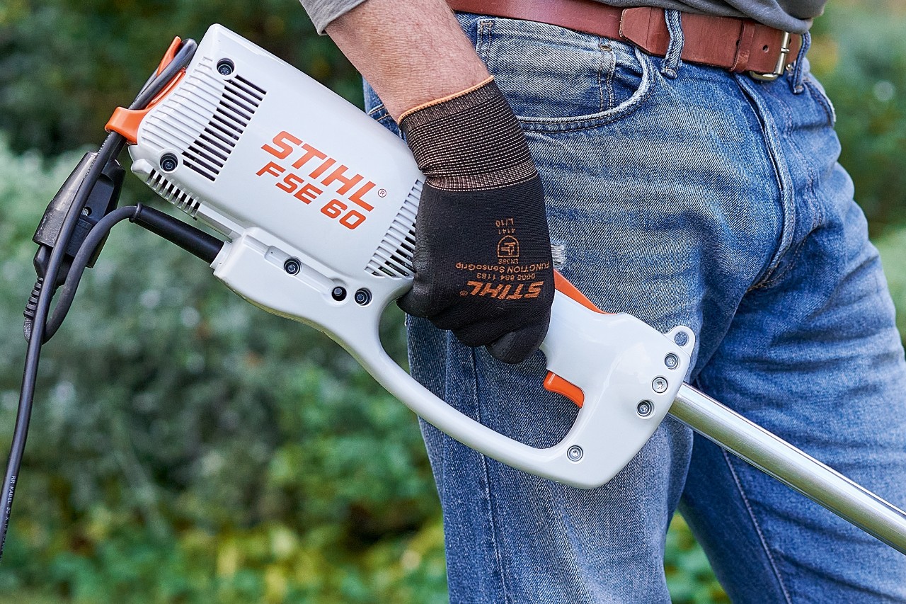 Egy férfi kapcsolókkal kikapcsolja a STIHL FSE 60 elektromos szegélynyírót