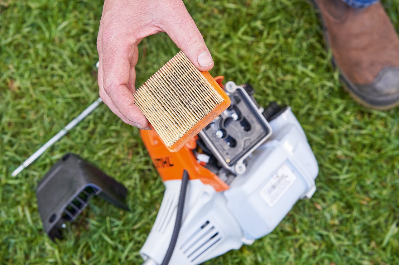 Egy férfi kiveszi egy STIHL motoros kasza légszűrőjét a tisztításhoz 