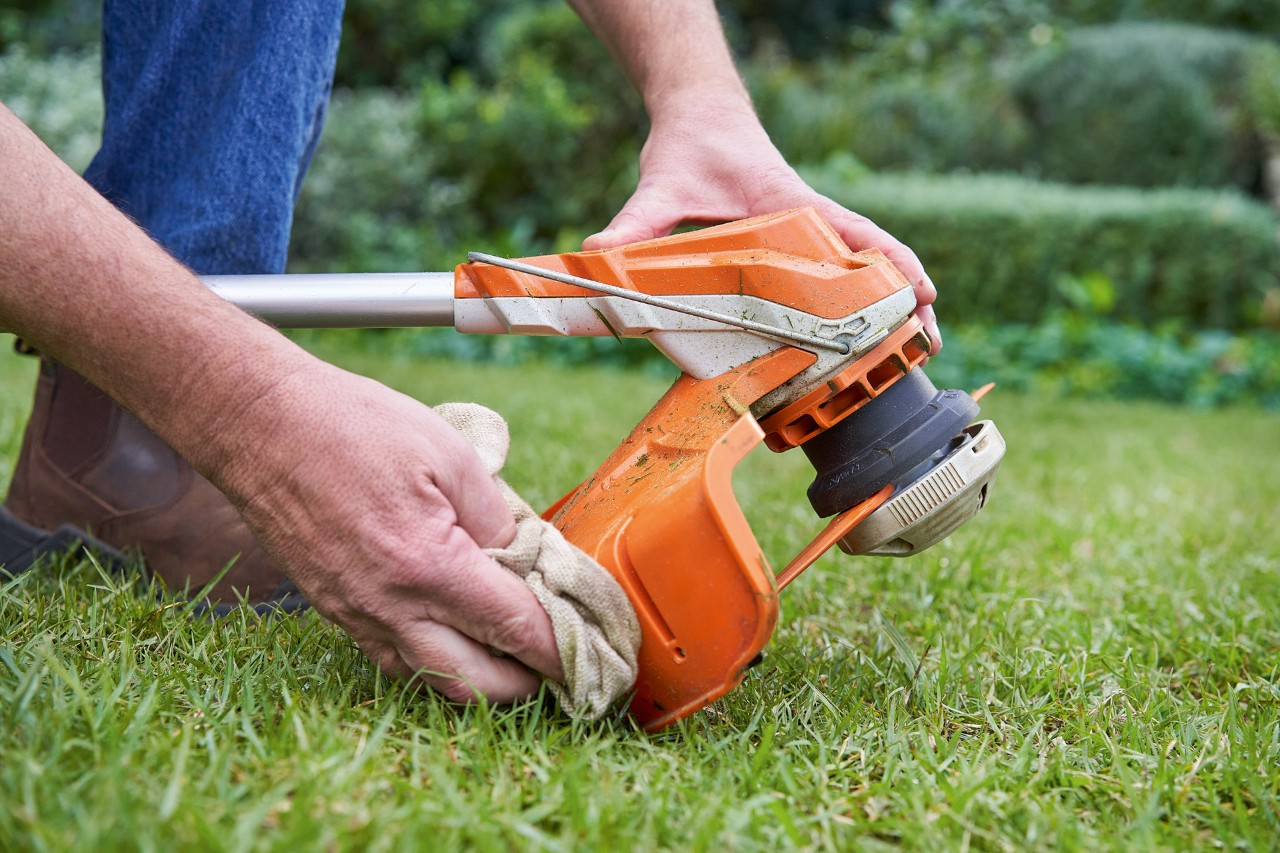 Egy férfi nedves törlőkendővel tisztítja a STIHL motoros kasza védőburkolatát