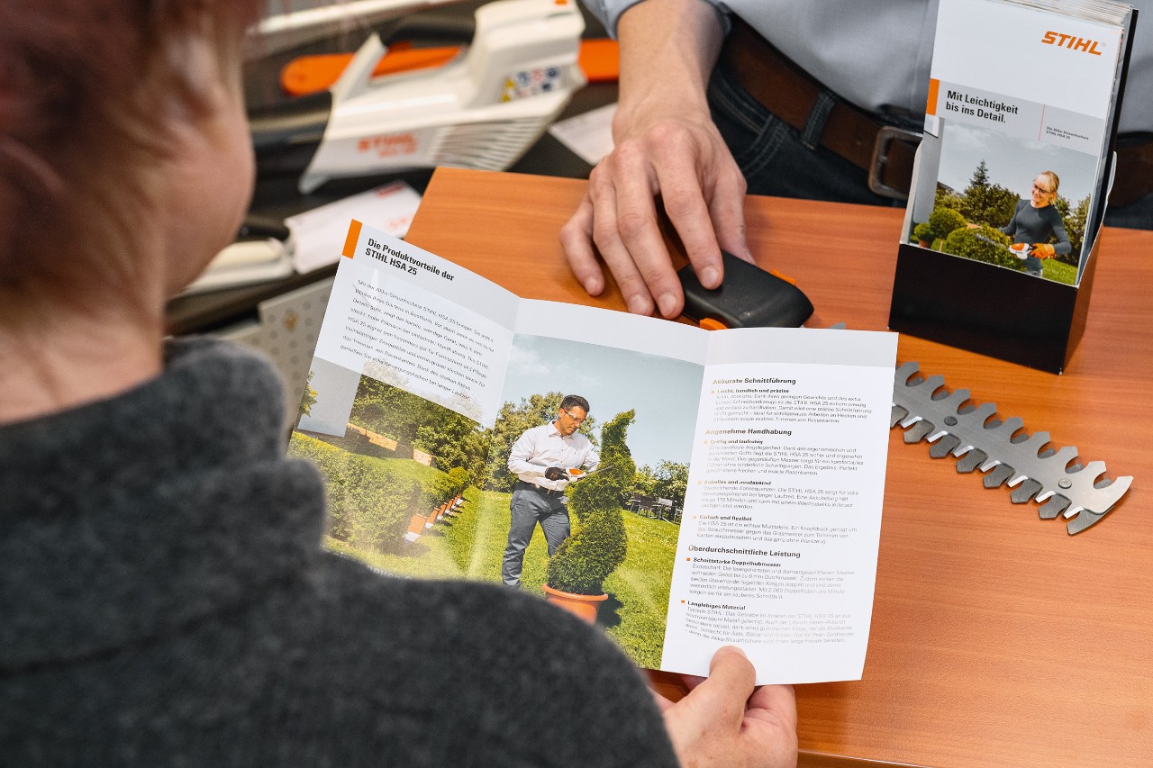 Egy ember a STIHL HSA 25 termékelőnyeiről olvas egy prospektusban