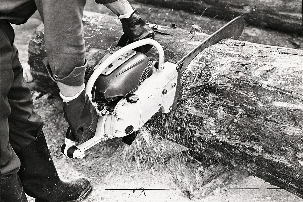 Régi fekete-fehér felvétel, amelyen egy ember a STIHL Contra motorfűrésszel fát vág 