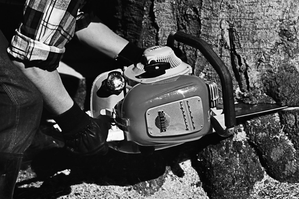 Régebbi fekete-fehér fénykép, amelyen valaki fát vág a STIHL Contra láncfűrésszel