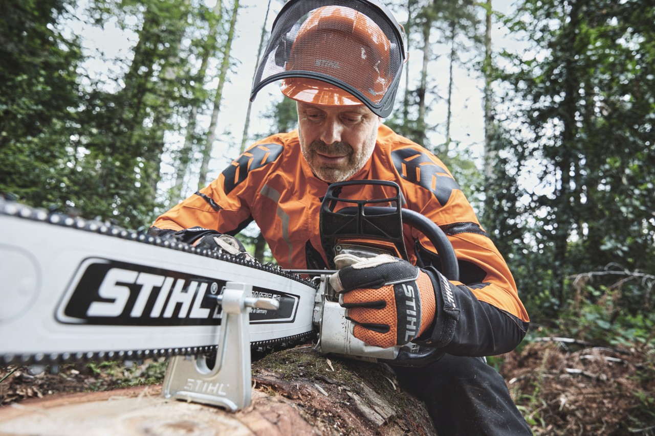 Egy védőfelszerelést viselő férfi STIHL motoros fűrésszel dolgozik az erdőben