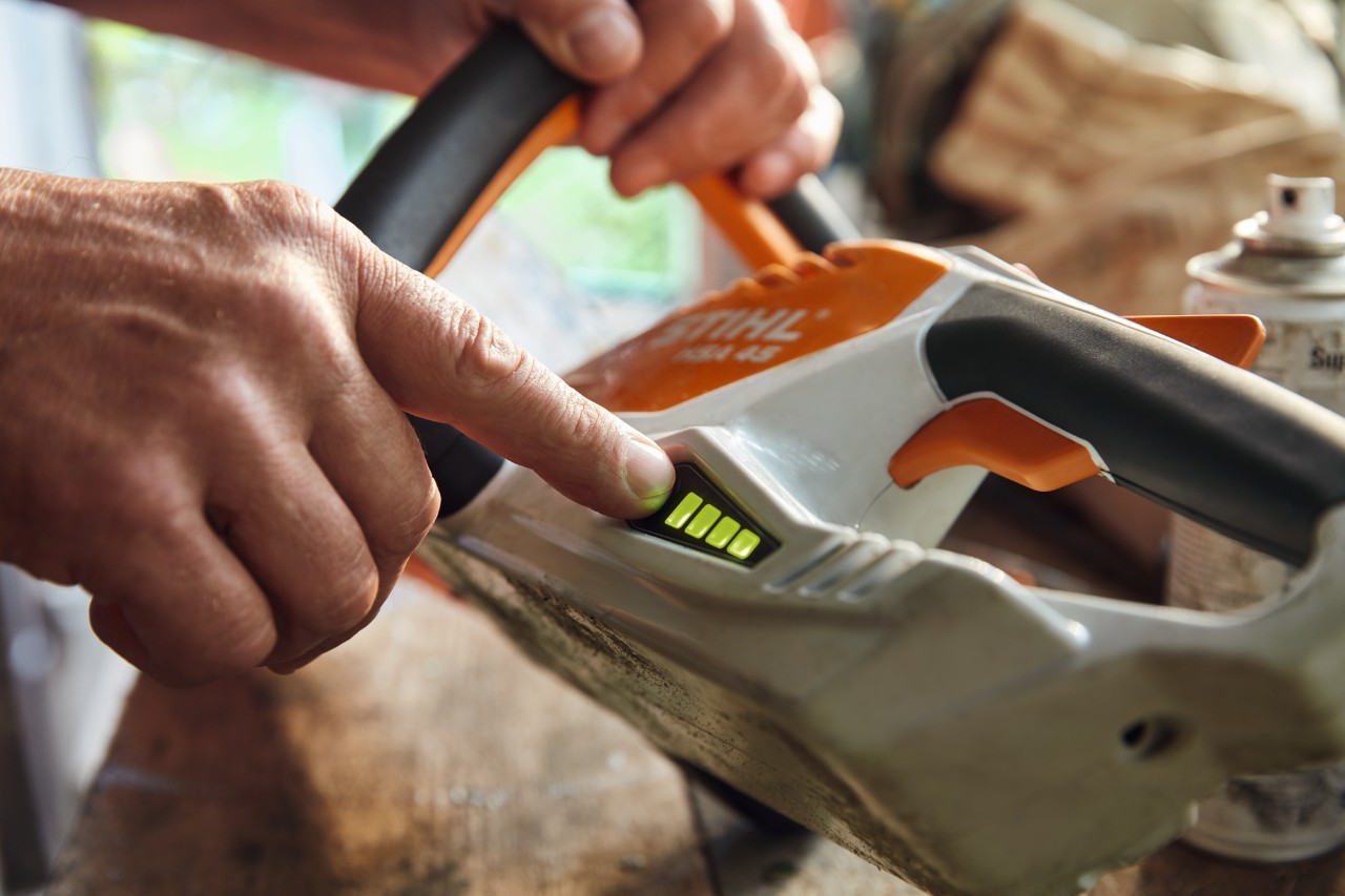 Valaki ellenőrzi a STIHL HSA 45 akkumulátoros sövénynyíró töltöttségi szintjét.