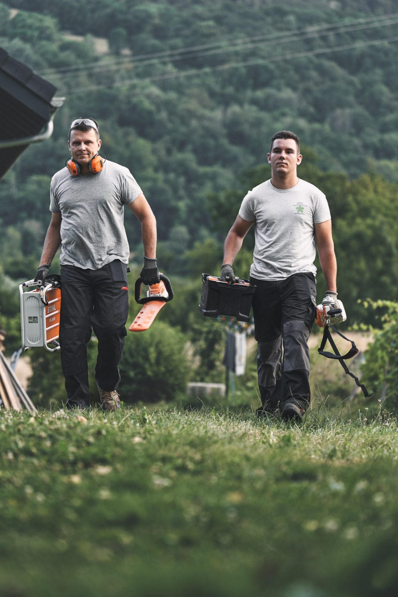 Két szakember fut egy réten STIHL akkumulátoros készülékekkel
