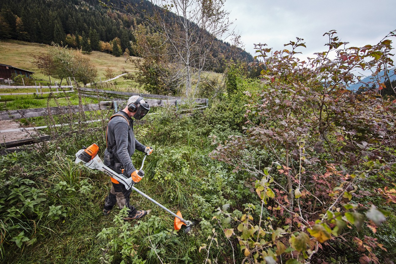 Védőfelszerelésben dolgozó férfi sűrű aljnövényzetet nyír egy STIHL FS 311 benzinmotoros kaszával