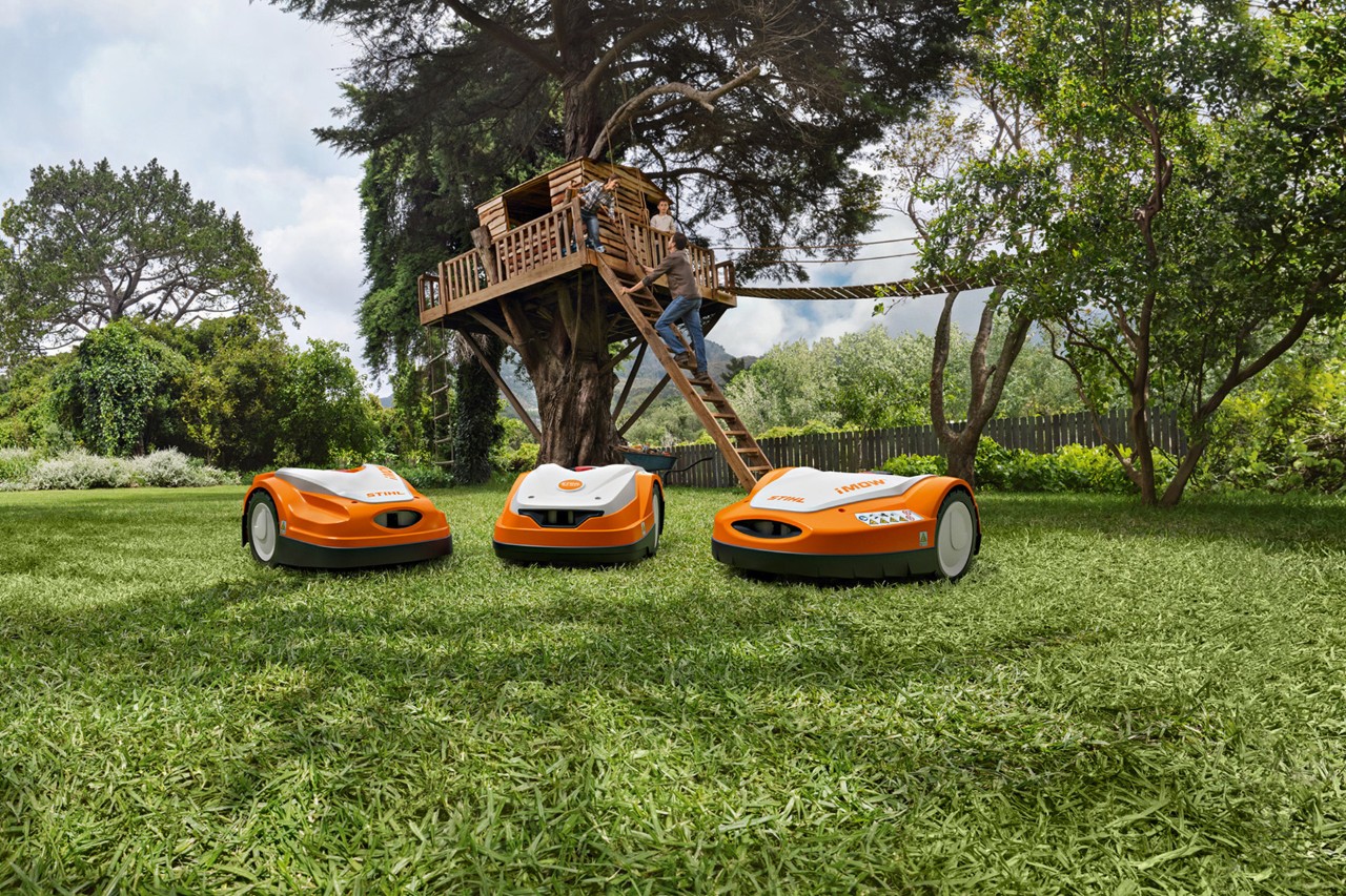 A különböző STIHL iMOW® robotfűnyírók zöld gyepen a kertben