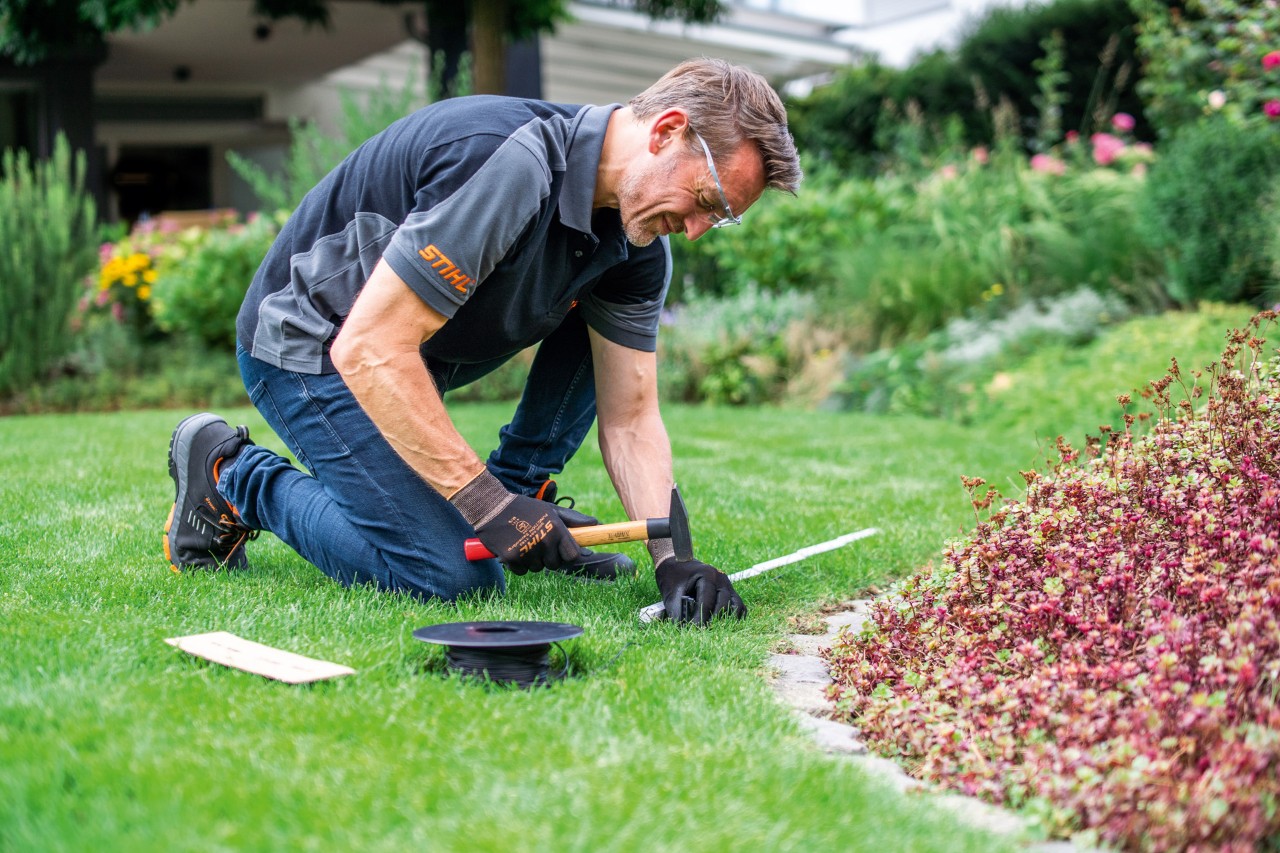 Egy STIHL szakkereskedő a határolóhuzal lefektetése közben
