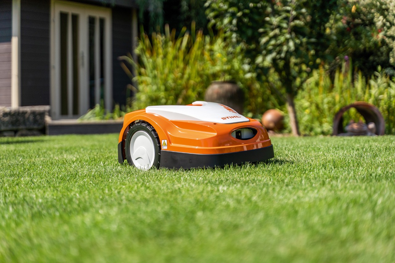 STIHL iMOW® RMI 422 robotfűnyíró zöld gyepen, egy ház előtt 
